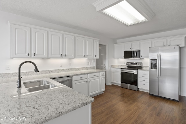 kitchen featuring a sink, appliances with stainless steel finishes, dark wood-style floors, white cabinetry, and light stone countertops
