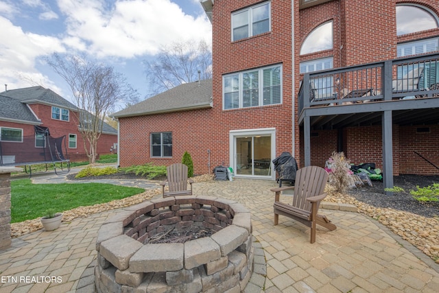 231 Gwinhurst Rd, Knoxville, TN 37934 - rear view of house featuring a trampoline, a patio, a fire pit, and brick siding