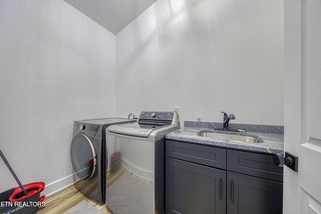 231 Gwinhurst Rd, Knoxville, TN 37934 - washroom featuring baseboards, a sink, light wood-style floors, cabinet space, and washing machine and clothes dryer