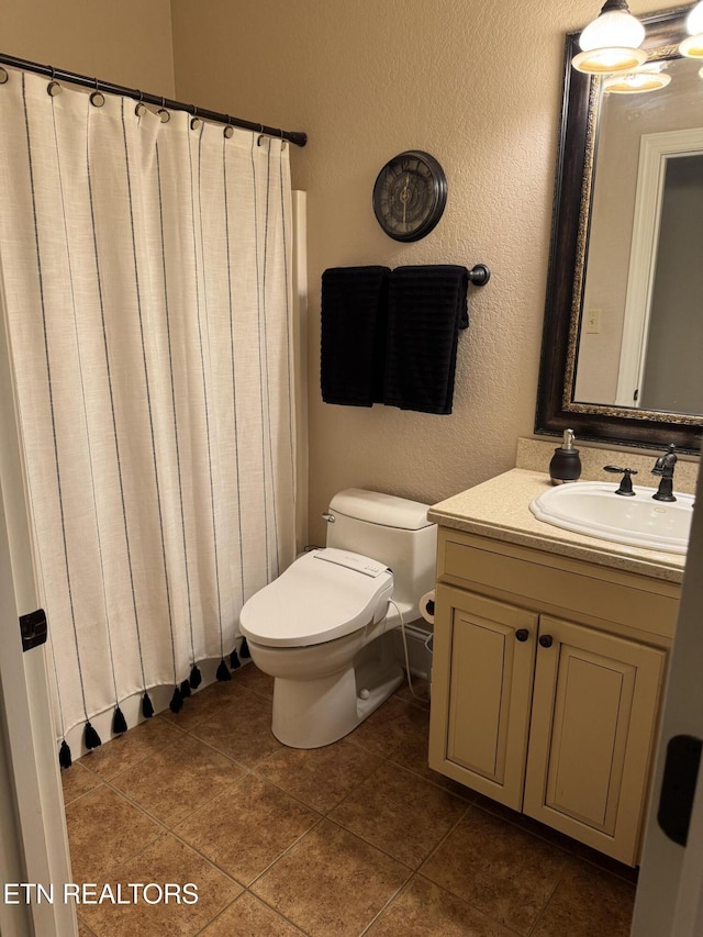 bathroom with a textured wall, tile patterned floors, vanity, and toilet