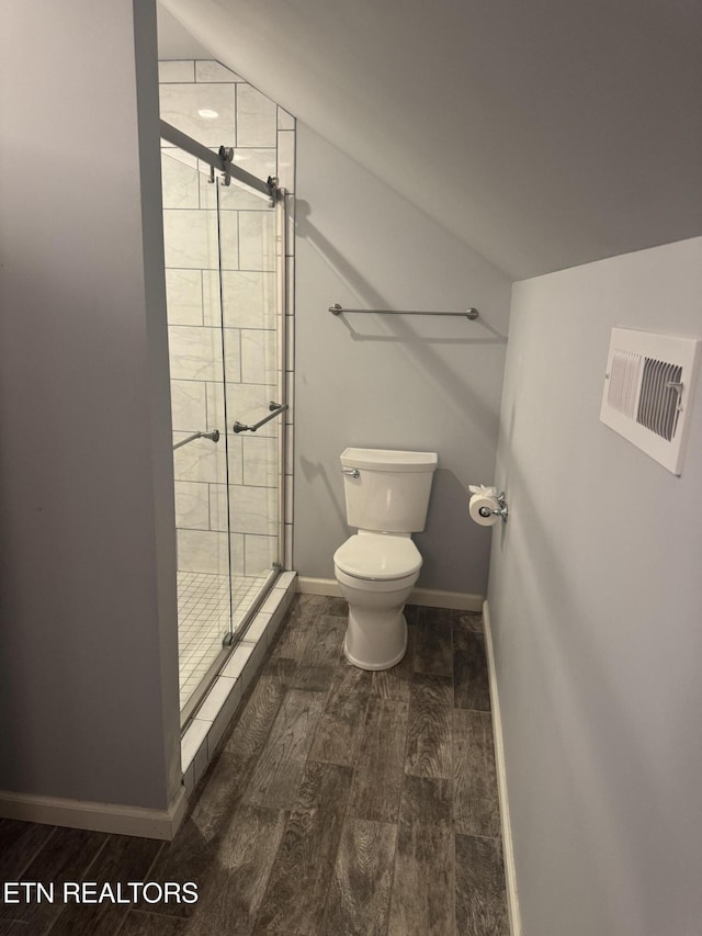 bathroom featuring baseboards, toilet, a shower stall, wood finished floors, and lofted ceiling
