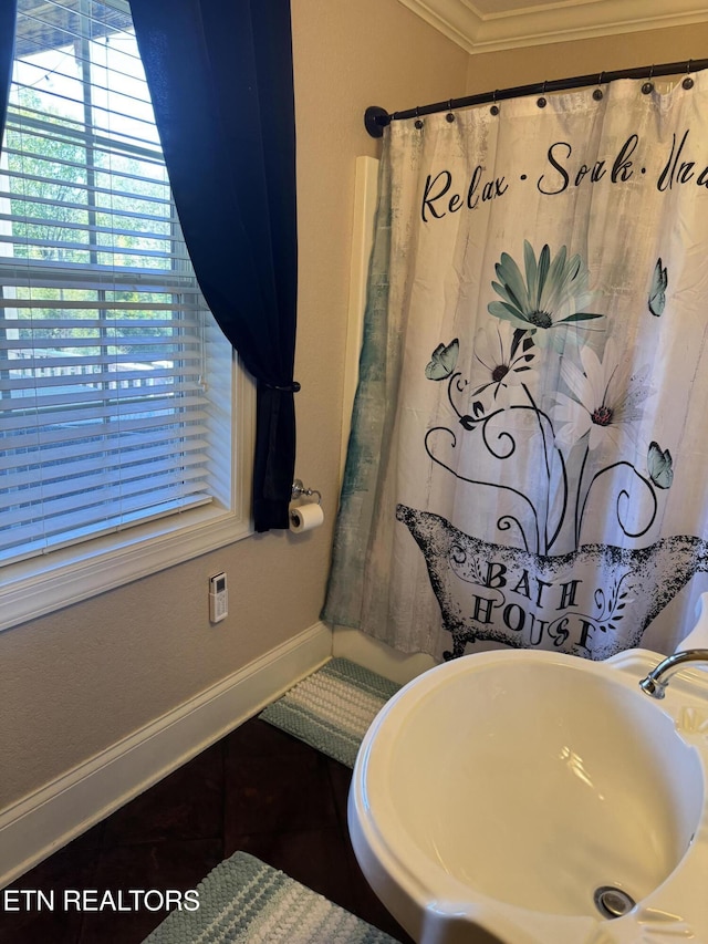 bathroom with a sink, baseboards, curtained shower, and crown molding