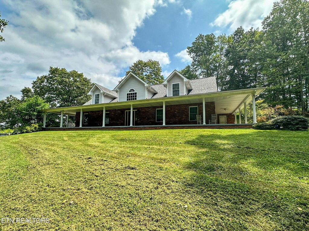 farmhouse-style home featuring brick siding, roof with shingles, and a front yard