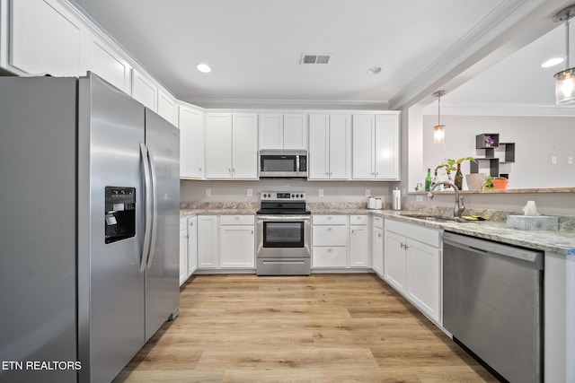 kitchen with visible vents, a sink, white cabinetry, appliances with stainless steel finishes, and crown molding
