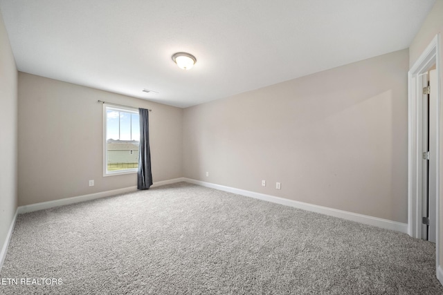 empty room with carpet flooring, visible vents, and baseboards