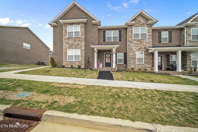 multi unit property with brick siding, cooling unit, and a front yard
