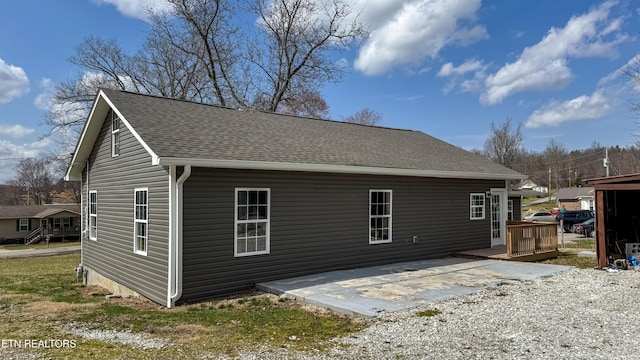 view of home's exterior with a wooden deck, a patio, and a shingled roof