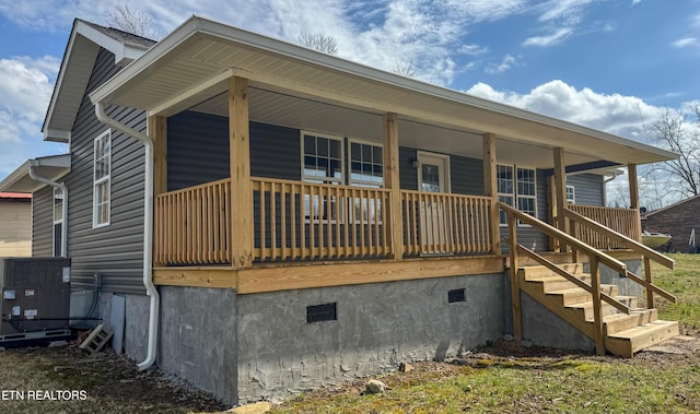 view of front facade featuring crawl space, central air condition unit, covered porch, and stairs