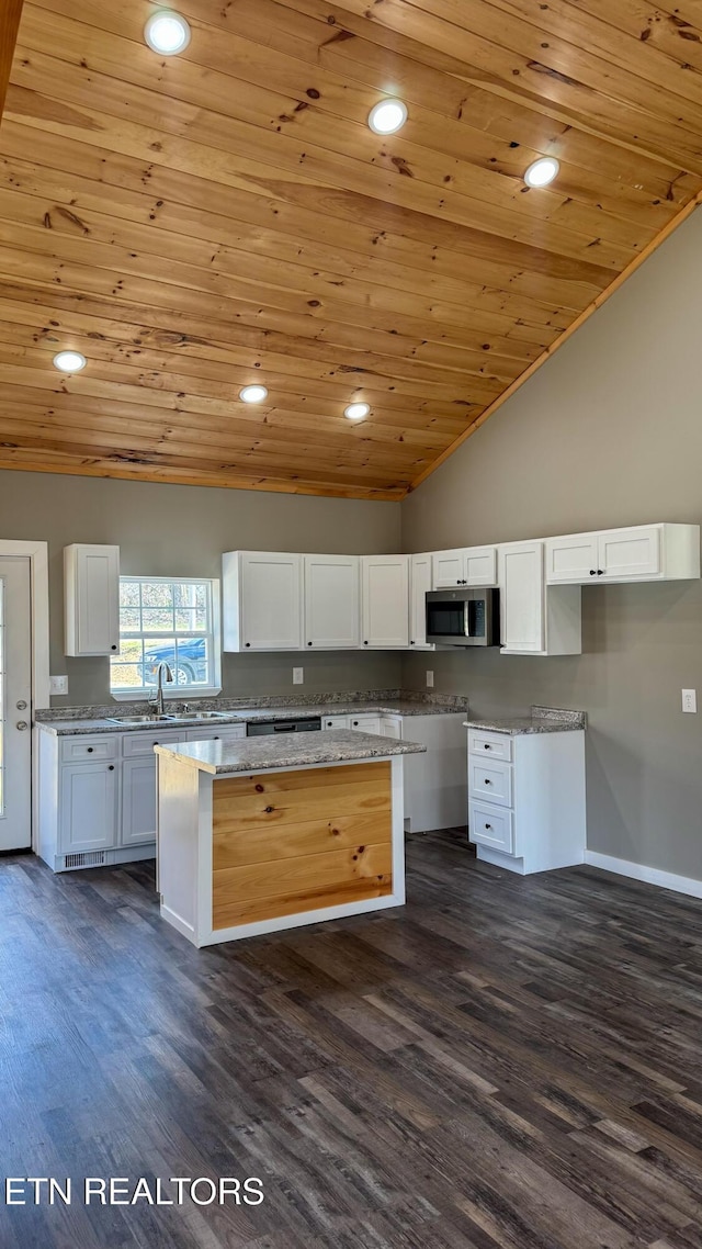 kitchen featuring stainless steel microwave, dark wood-type flooring, and white cabinets