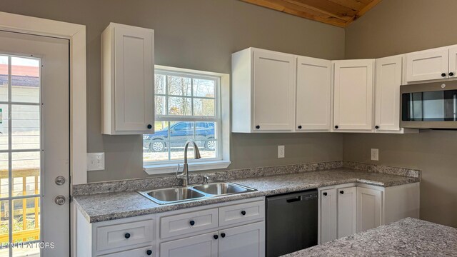 kitchen featuring stainless steel microwave, dishwasher, light countertops, white cabinetry, and a sink