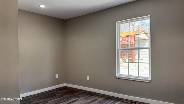 spare room with visible vents, baseboards, and dark wood-style flooring