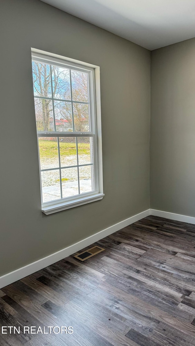unfurnished room featuring dark wood-type flooring, baseboards, and visible vents