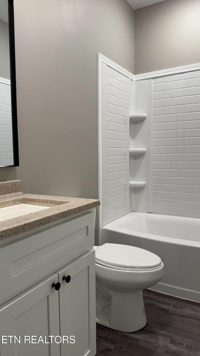 full bathroom featuring toilet, washtub / shower combination, vanity, and wood finished floors