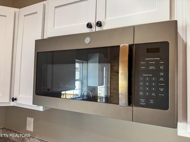 room details featuring stainless steel microwave and white cabinets