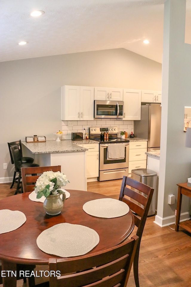 dining area with recessed lighting, baseboards, light wood finished floors, and vaulted ceiling