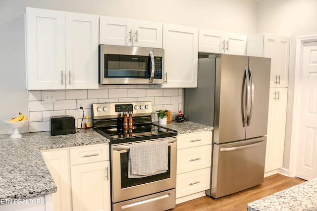 kitchen featuring white cabinetry, light wood-type flooring, backsplash, and stainless steel appliances