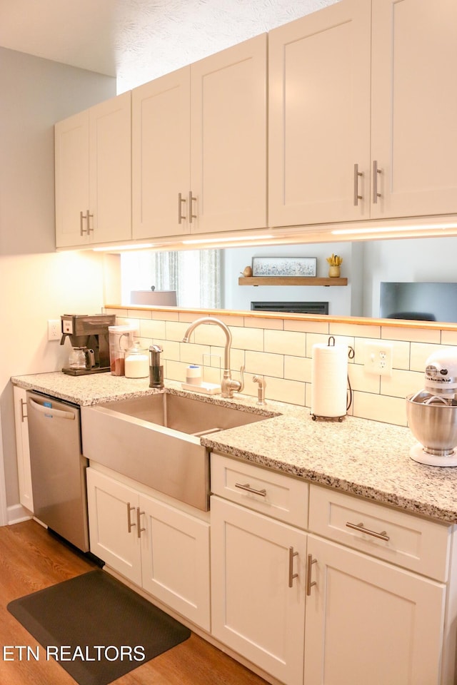 kitchen featuring backsplash, a sink, white cabinets, and stainless steel dishwasher