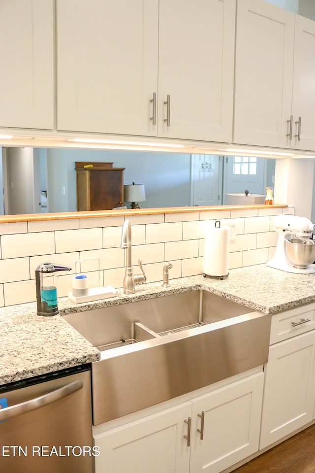 kitchen with light stone counters, a sink, white cabinets, dishwasher, and tasteful backsplash