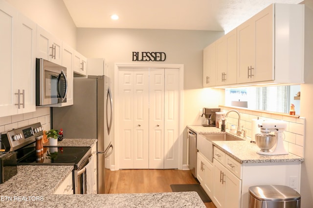 kitchen with light wood-style flooring, white cabinets, appliances with stainless steel finishes, and a sink