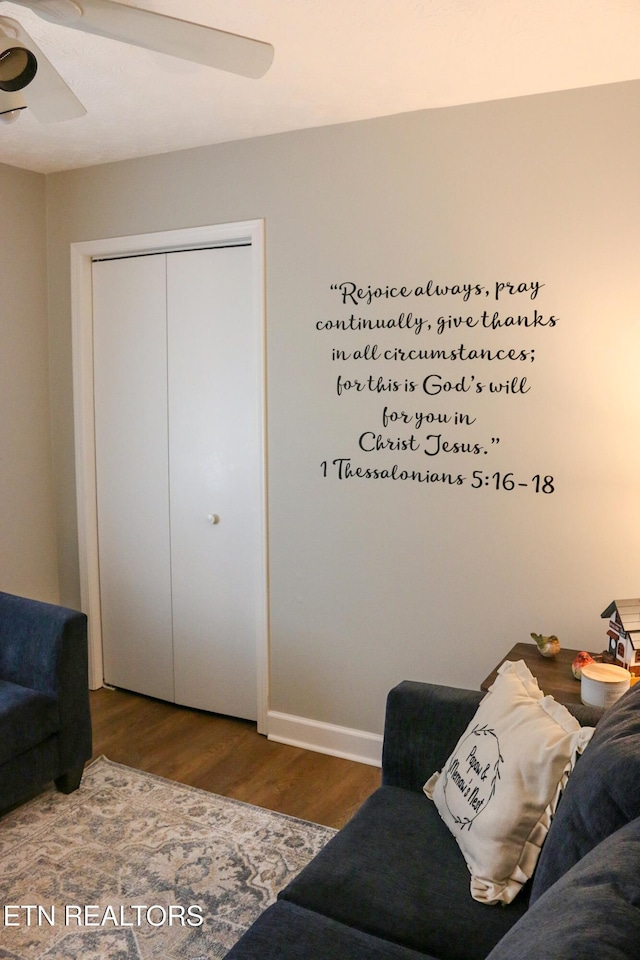 living area with baseboards, wood finished floors, and ceiling fan