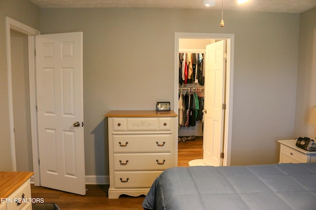 bedroom with a walk in closet, a closet, and dark wood-style flooring