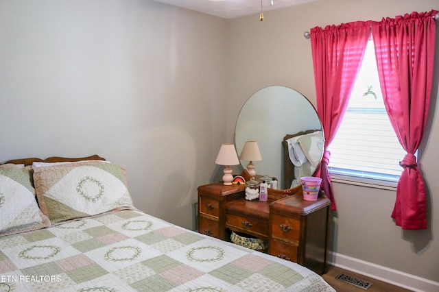 bedroom with wood finished floors, baseboards, and visible vents