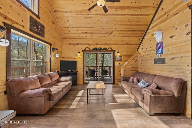 living room featuring wooden ceiling, wooden walls, lofted ceiling, and ceiling fan