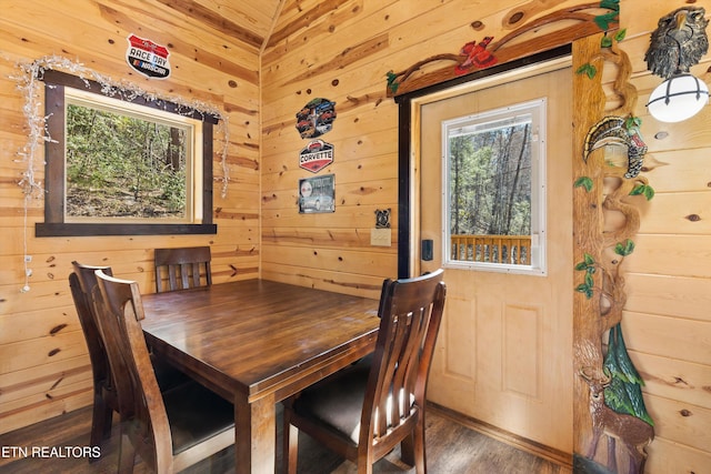 dining space featuring a wealth of natural light, wood walls, and wood finished floors