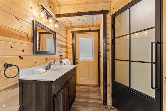 bathroom with wooden ceiling, vanity, wood walls, and wood finished floors