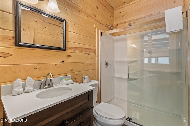 bathroom with a stall shower, wooden walls, vanity, and toilet