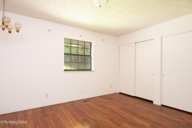 123 Manor Rd, Clinton, TN 37716 - unfurnished bedroom featuring wood finished floors, a chandelier, a textured ceiling, and two closets