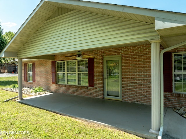 view of side of home featuring brick siding, a patio area, and ceiling fan