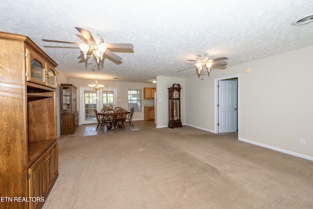 living area with ceiling fan with notable chandelier, visible vents, a textured ceiling, and light colored carpet