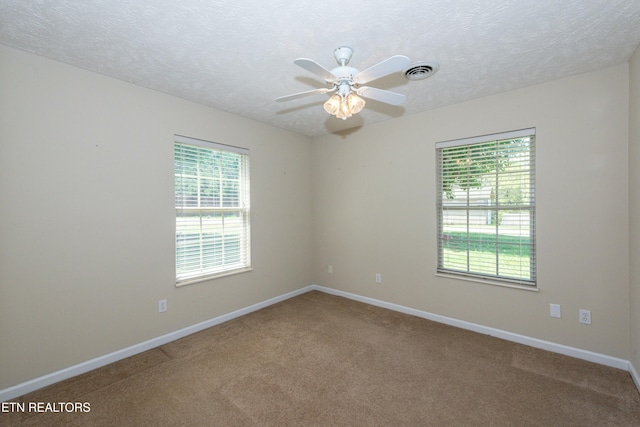 carpeted spare room with baseboards, a ceiling fan, a textured ceiling, and visible vents