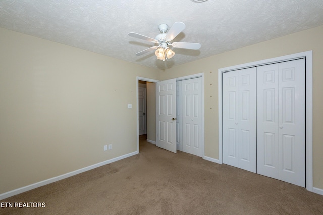 unfurnished bedroom featuring baseboards, carpet floors, a textured ceiling, and two closets