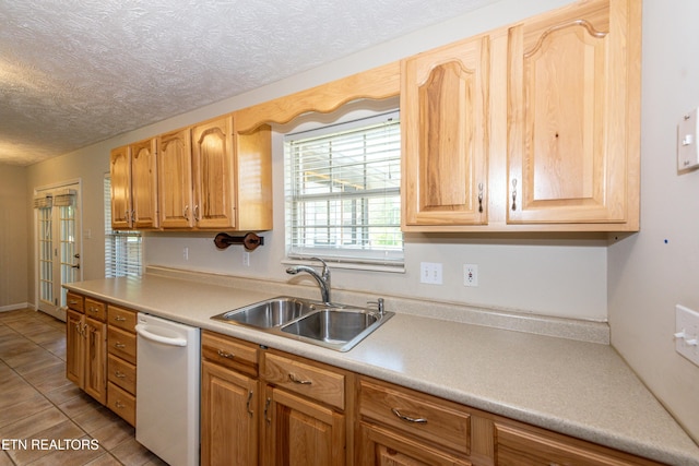 kitchen with light countertops, dishwasher, a sink, light tile patterned flooring, and a textured ceiling