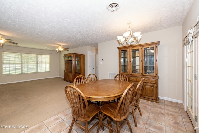 dining space with a textured ceiling, visible vents, light tile patterned floors, and ceiling fan with notable chandelier