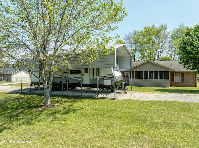 exterior space featuring a detached carport, a front lawn, and a sunroom