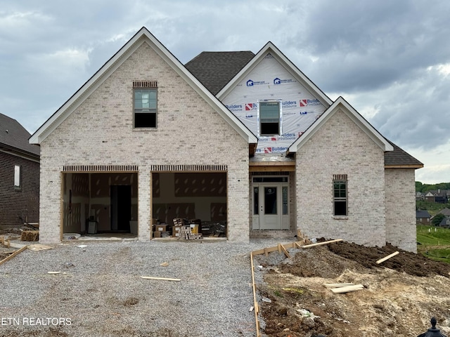 unfinished property with brick siding, roof with shingles, and a garage