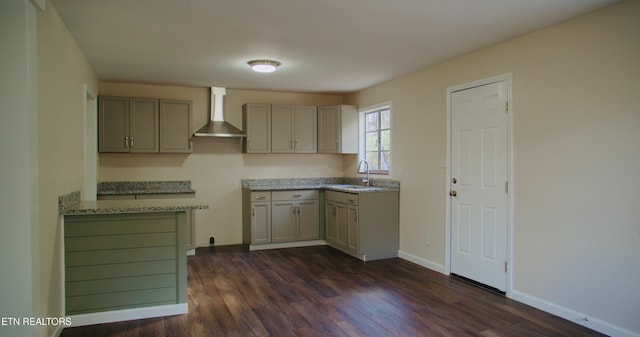 kitchen with baseboards, dark wood-style flooring, gray cabinetry, a sink, and wall chimney exhaust hood