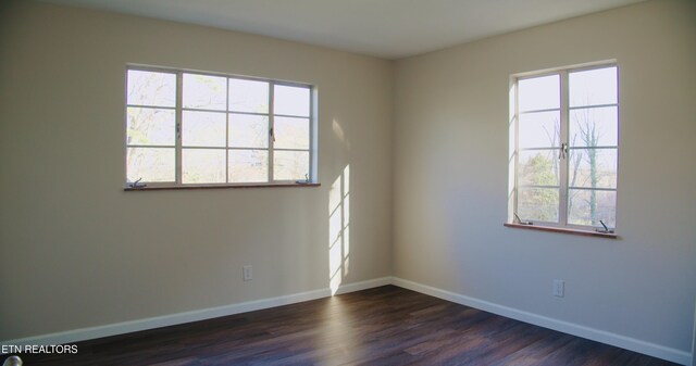 empty room featuring baseboards and dark wood-style flooring