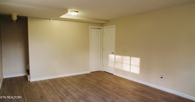 spare room featuring baseboards and wood finished floors