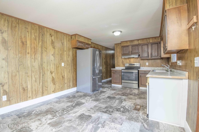 kitchen featuring light countertops, wood walls, a sink, and stainless steel appliances
