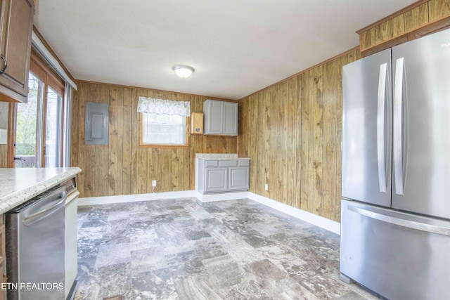 kitchen with baseboards, light countertops, wood walls, and stainless steel appliances
