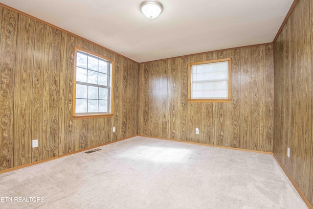 spare room featuring baseboards, visible vents, wood walls, and carpet floors