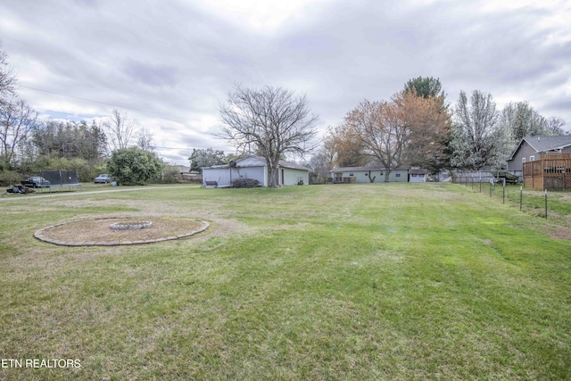 view of yard with fence, a garage, and a trampoline