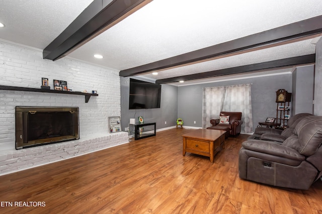 living area featuring beam ceiling, a textured ceiling, wood finished floors, a fireplace, and baseboards