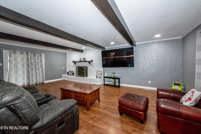 living area featuring beam ceiling, a textured ceiling, baseboards, and wood finished floors