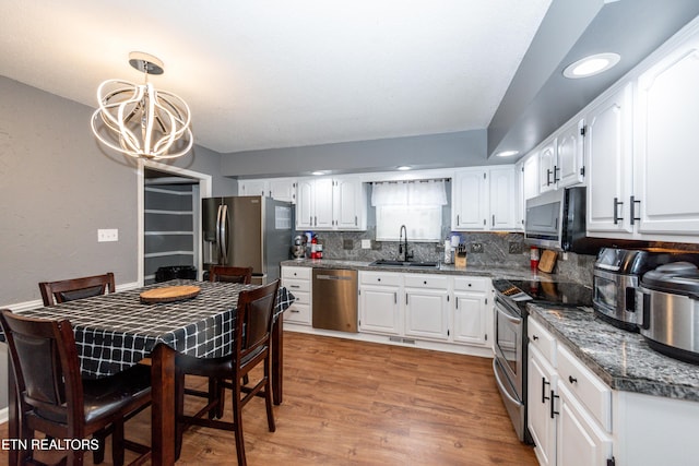 kitchen with backsplash, stainless steel appliances, light wood-style floors, and white cabinetry
