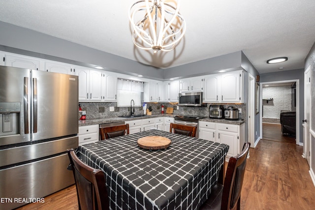 kitchen with a sink, dark wood-type flooring, white cabinets, appliances with stainless steel finishes, and tasteful backsplash